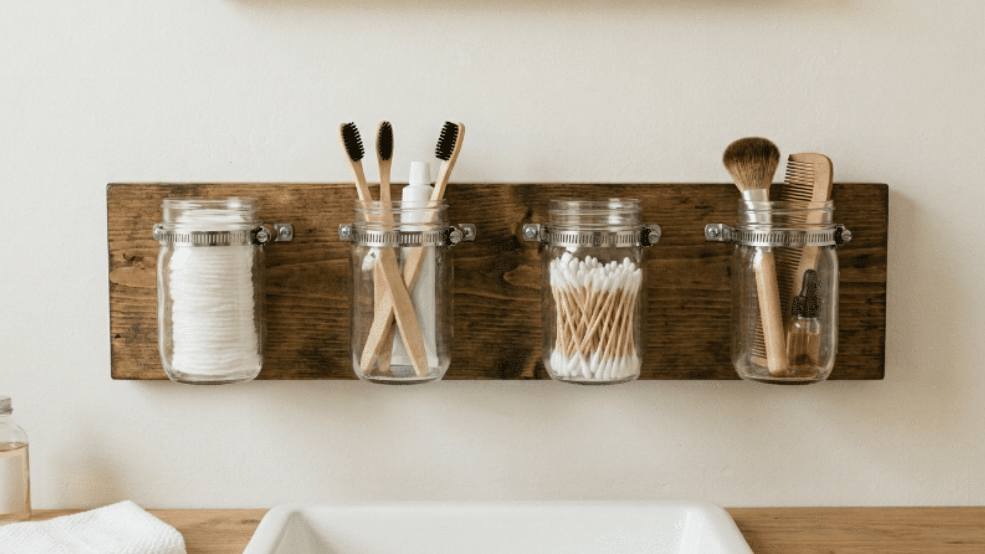 mason jar organizer mounted on bathroom wall with neatly arranged essentials
