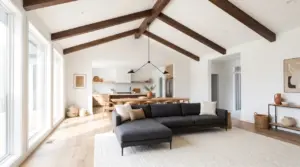 Modern vaulted ceiling living room with dark exposed beams, pendant light, low profile furniture anchored by oversized rug.