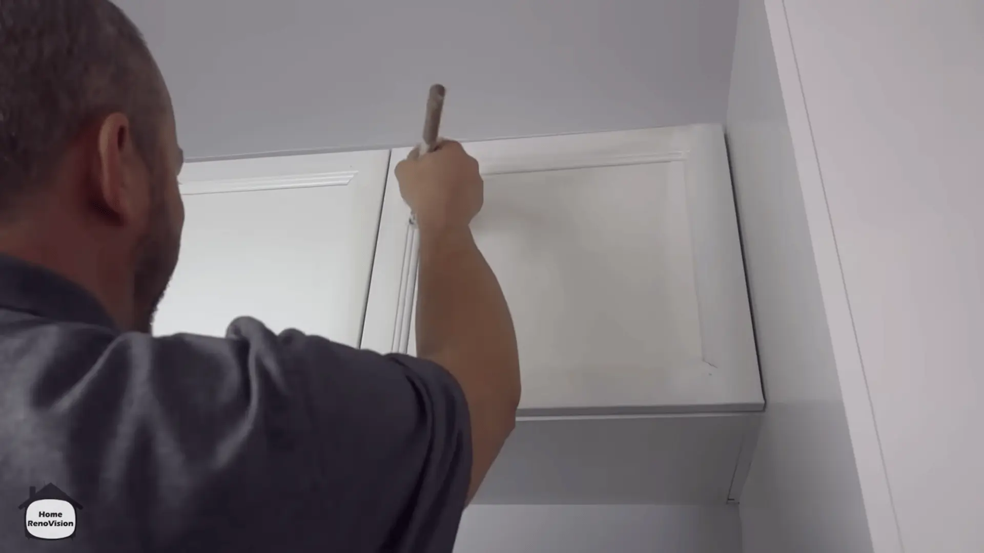 Applying the final coat of white paint after reinstalling the kitchen cabinet doors.