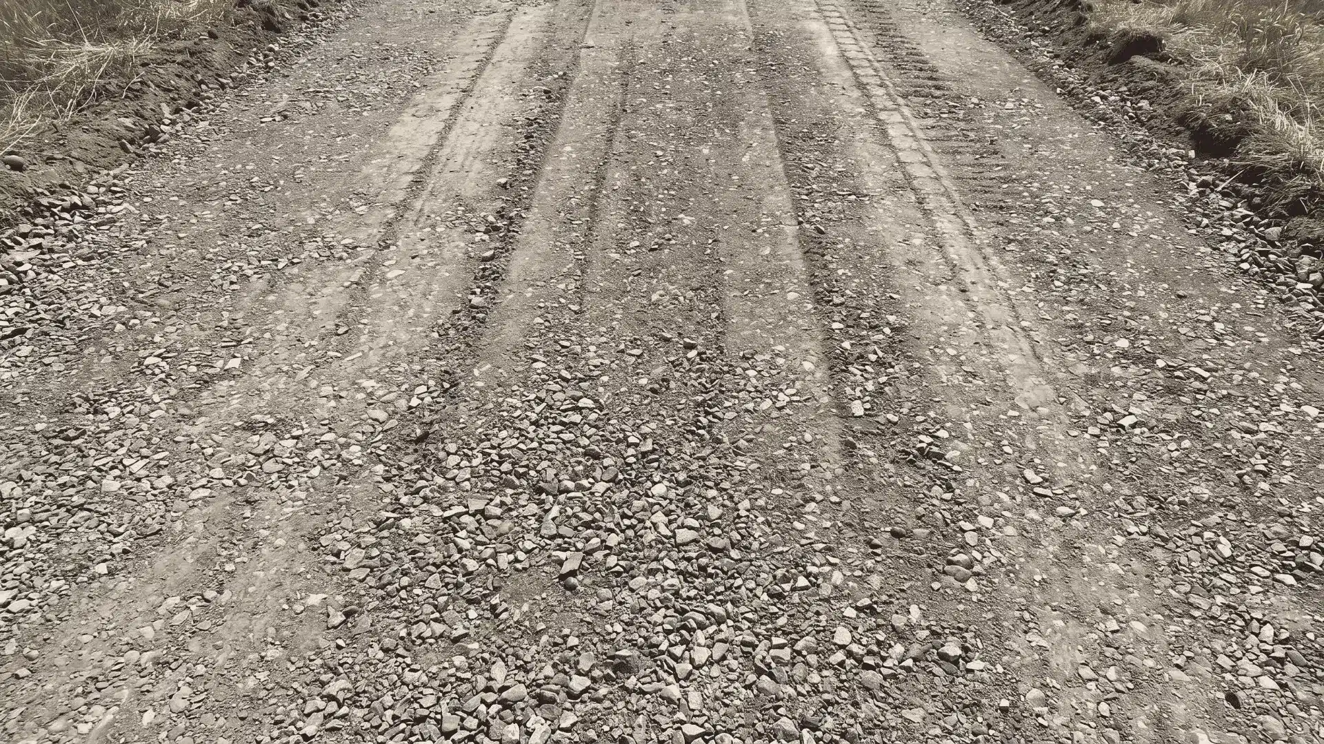 Compacted crusher run forming a dense binder layer beneath a gravel driveway surface.