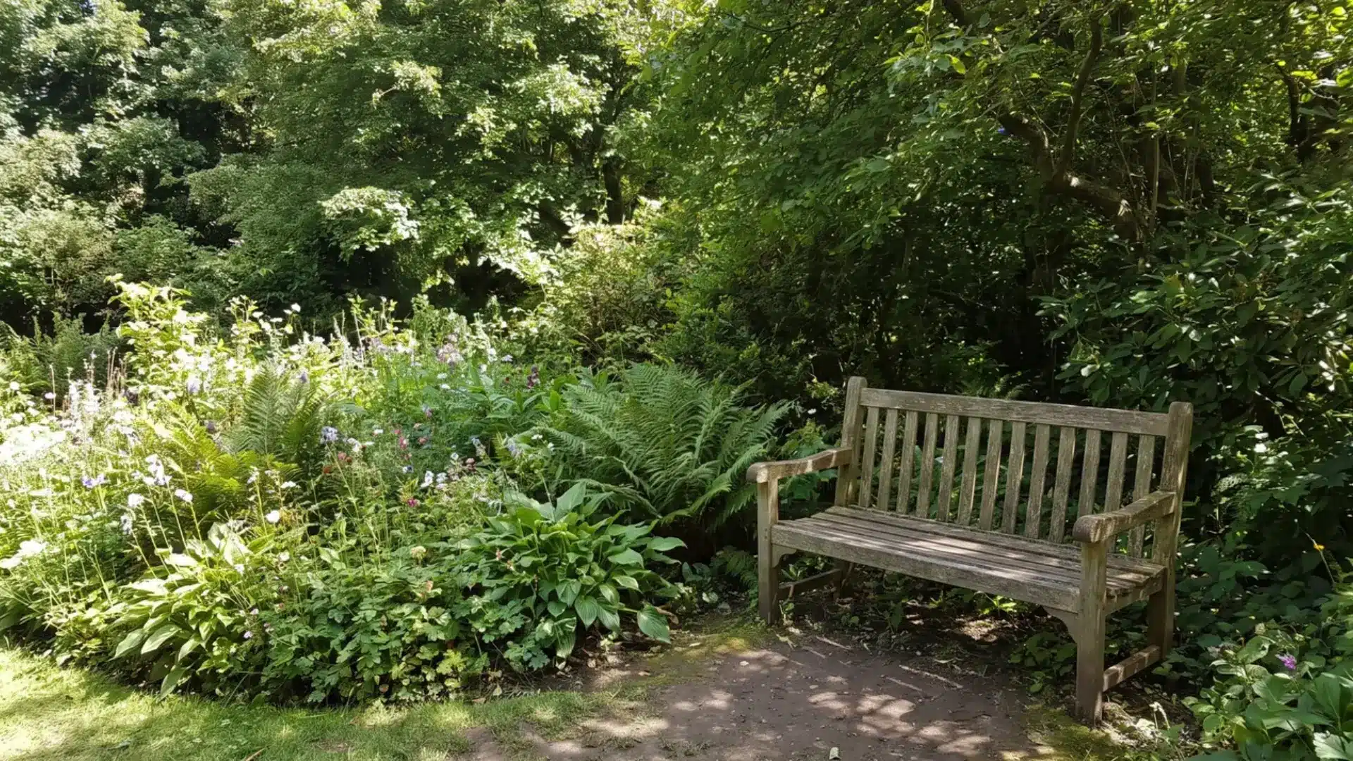 wooden bench tucked beside a shaded garden flower bed