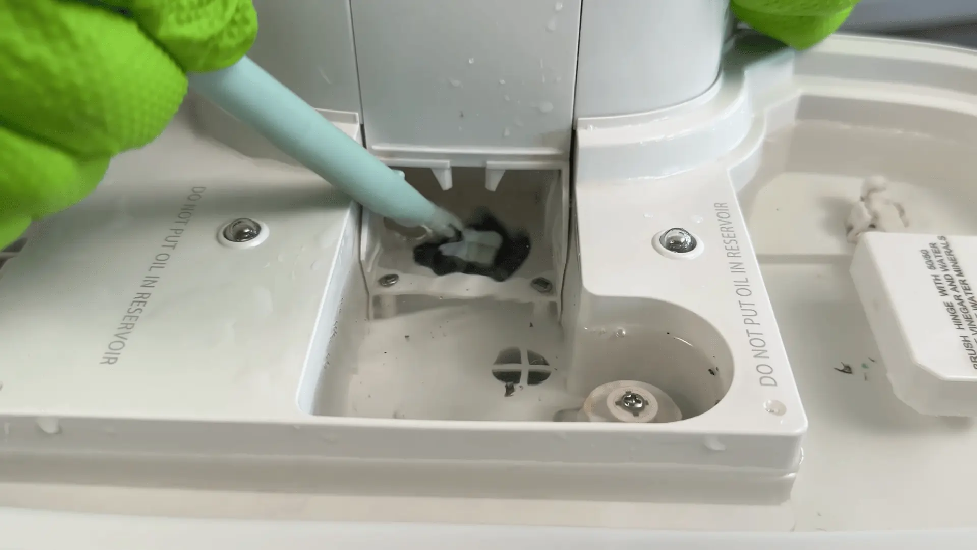 Person cleaning a humidifier base with a brush to remove buildup and residue from internal parts.