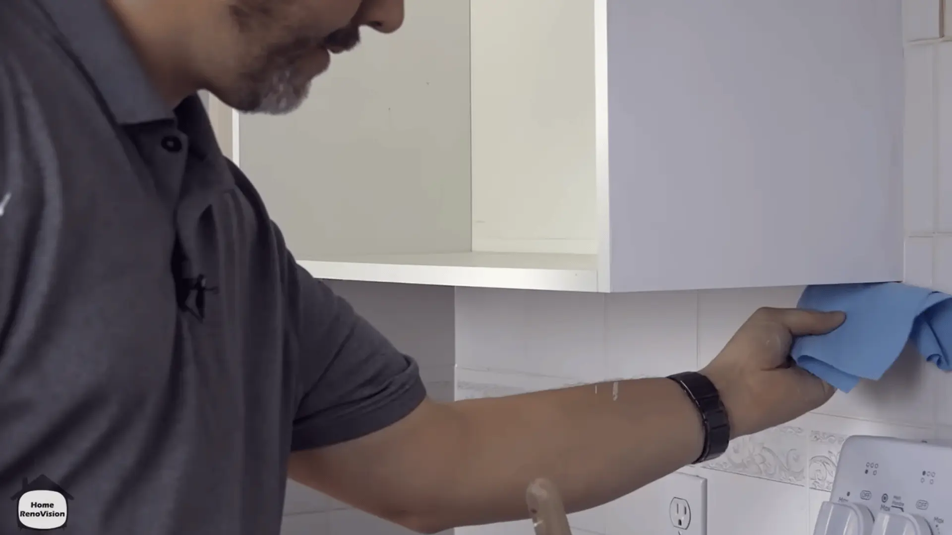 Wiping a fixed kitchen cabinet frame clean before sanding, priming, and painting it.