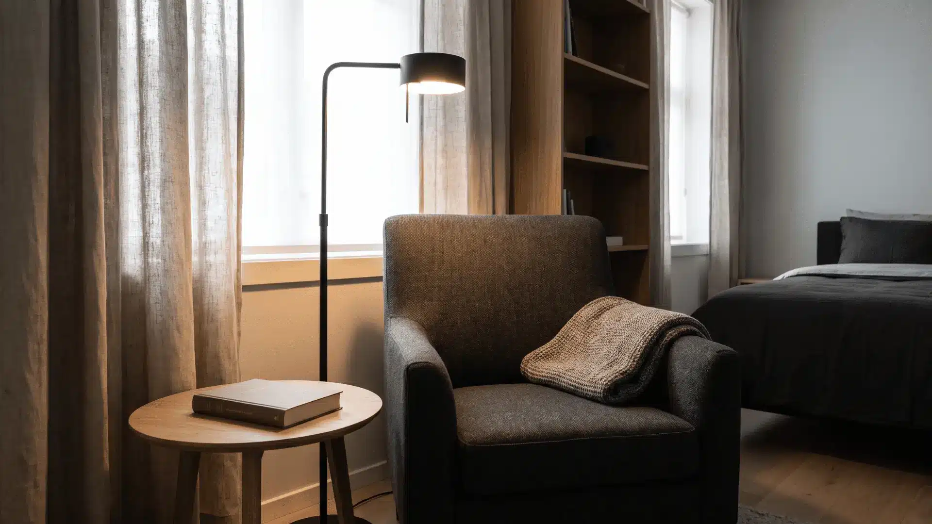 Men’s bedroom reading corner with a charcoal chair, floor lamp, and side table