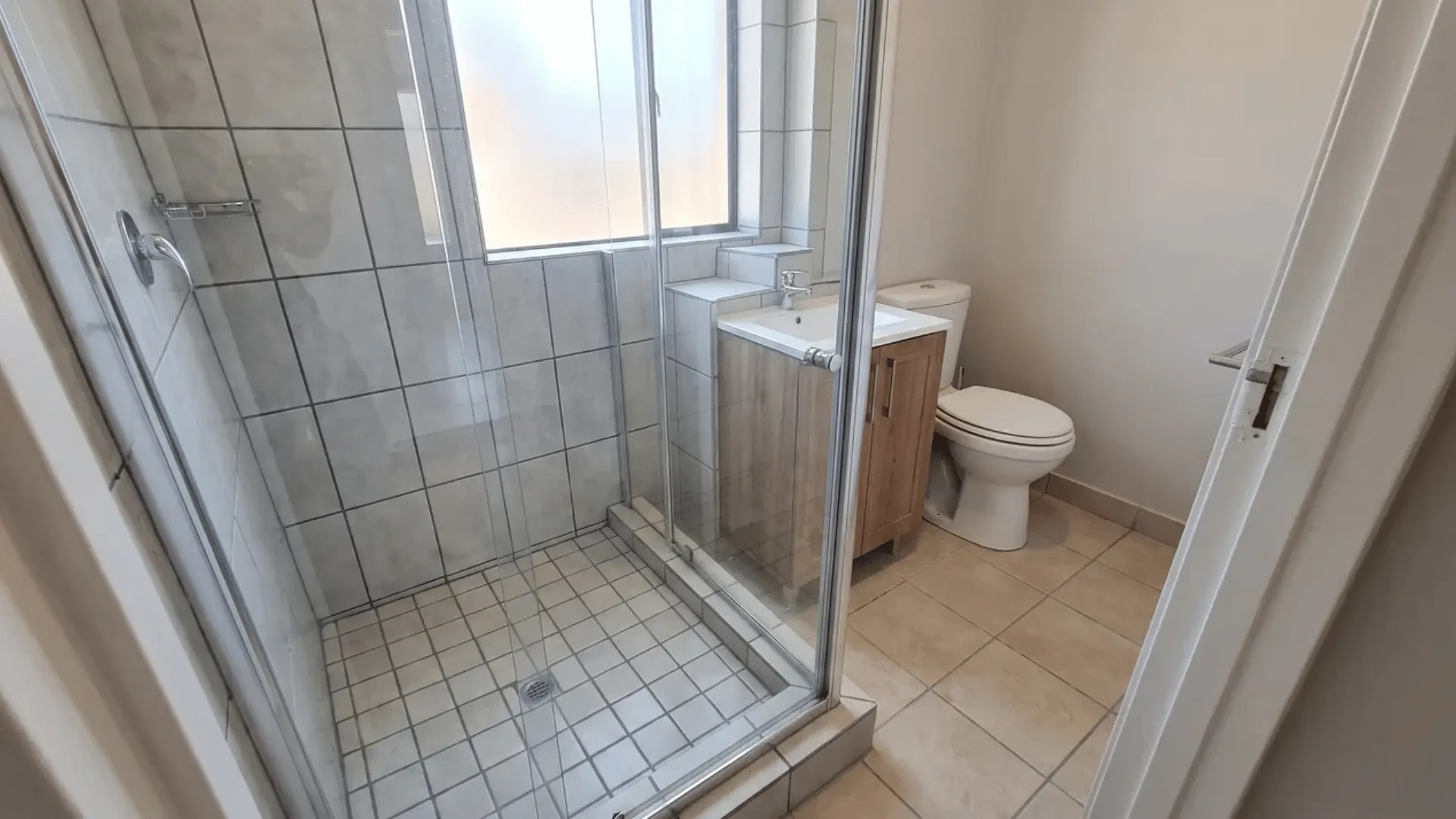 Full small bathroom with a walk-in shower using epoxy grout across the tiled shower walls and floor