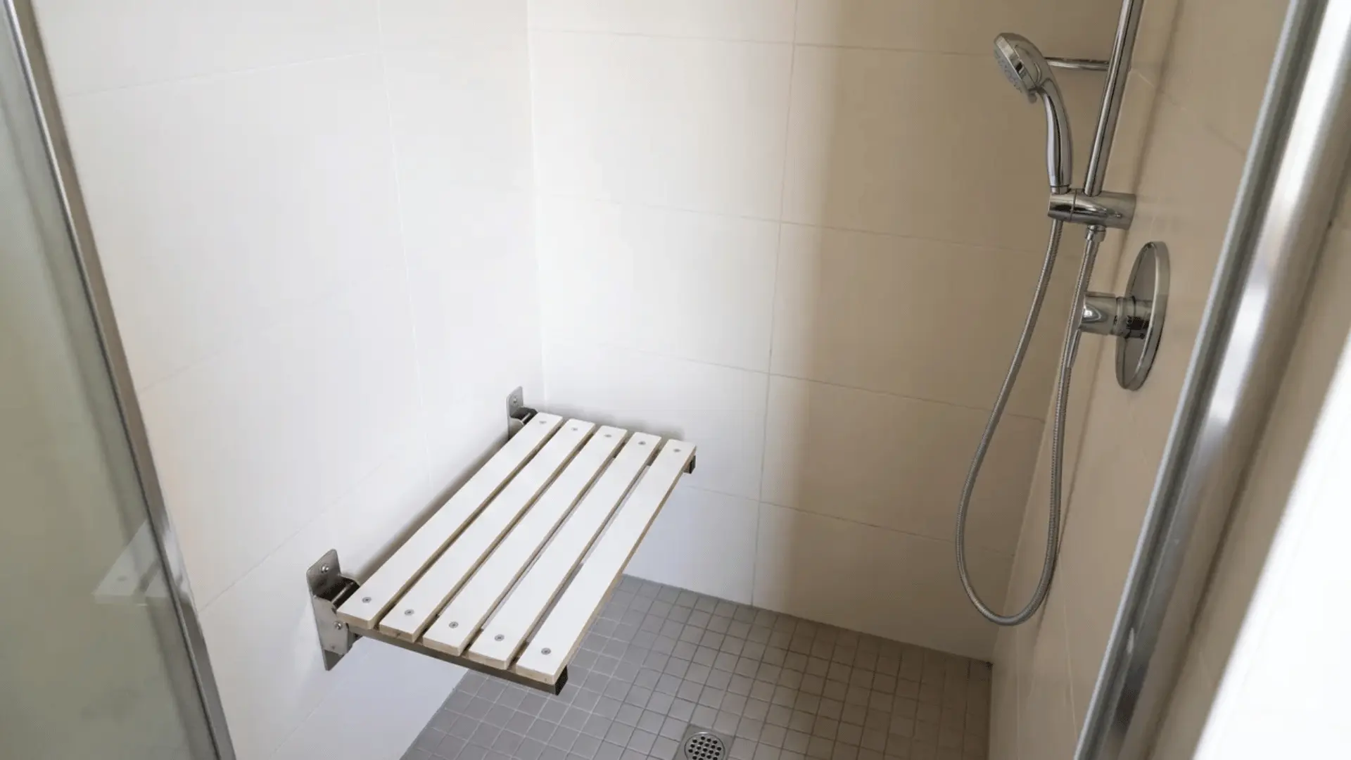 Fold-down shower seat mounted inside a small shower with open floor space around it