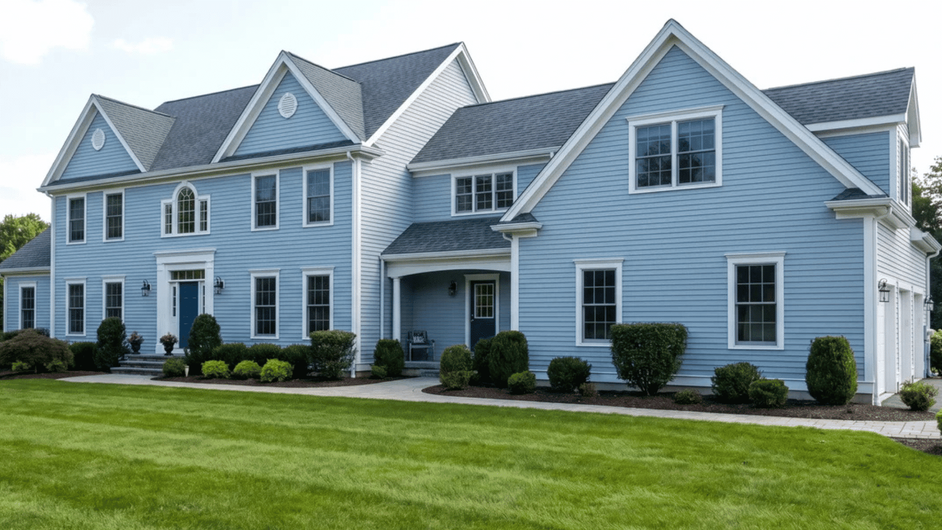 Large freshly painted house with a green lawn in front and clean exterior surfaces.