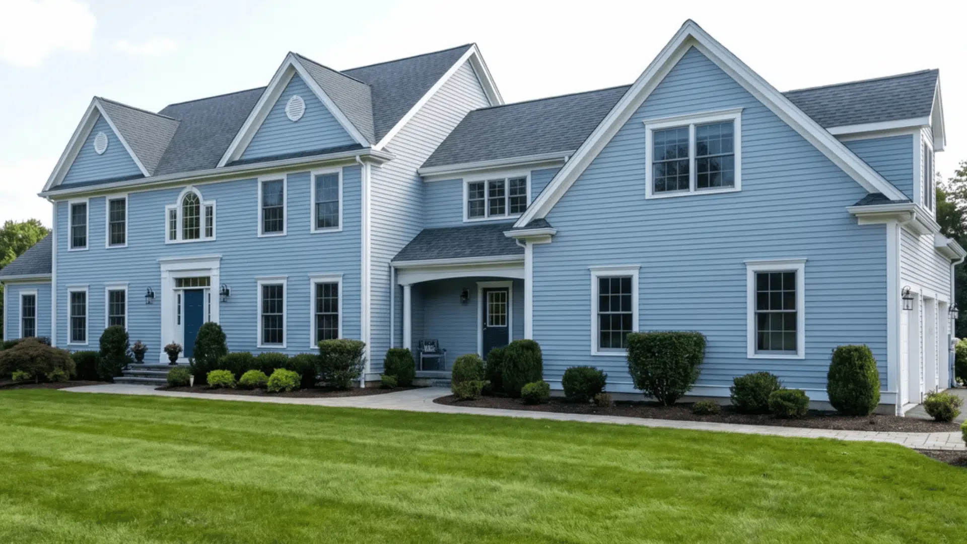 Large freshly painted house with a green lawn in front and clean exterior surfaces.
