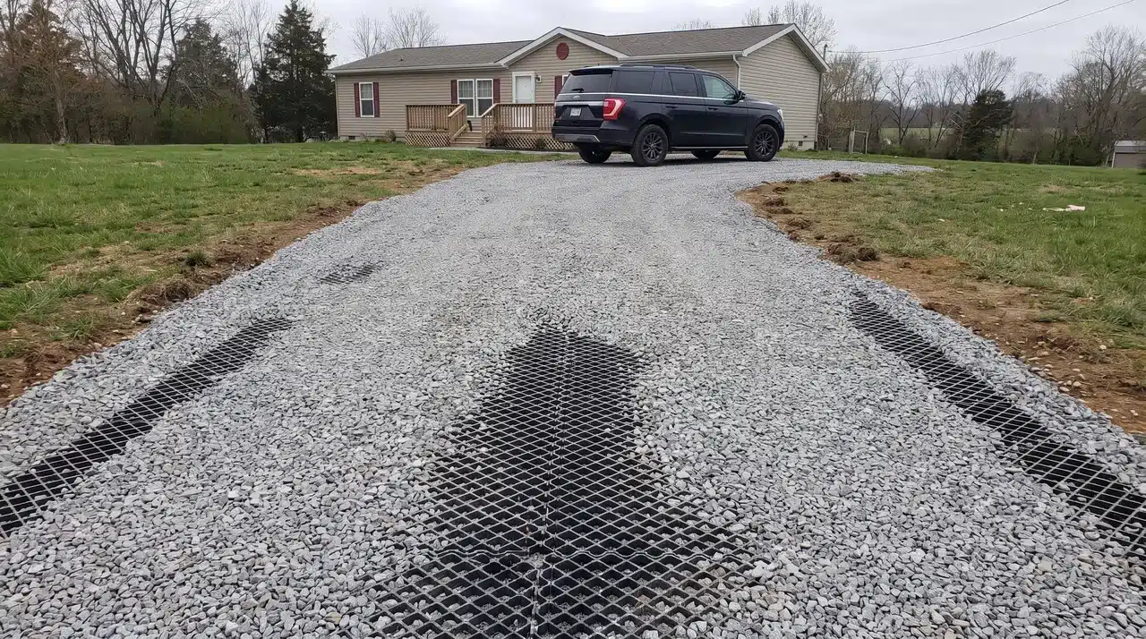 Gravel driveway with stabilizer grids filled with stone leading to a suburban home and parked SUV.