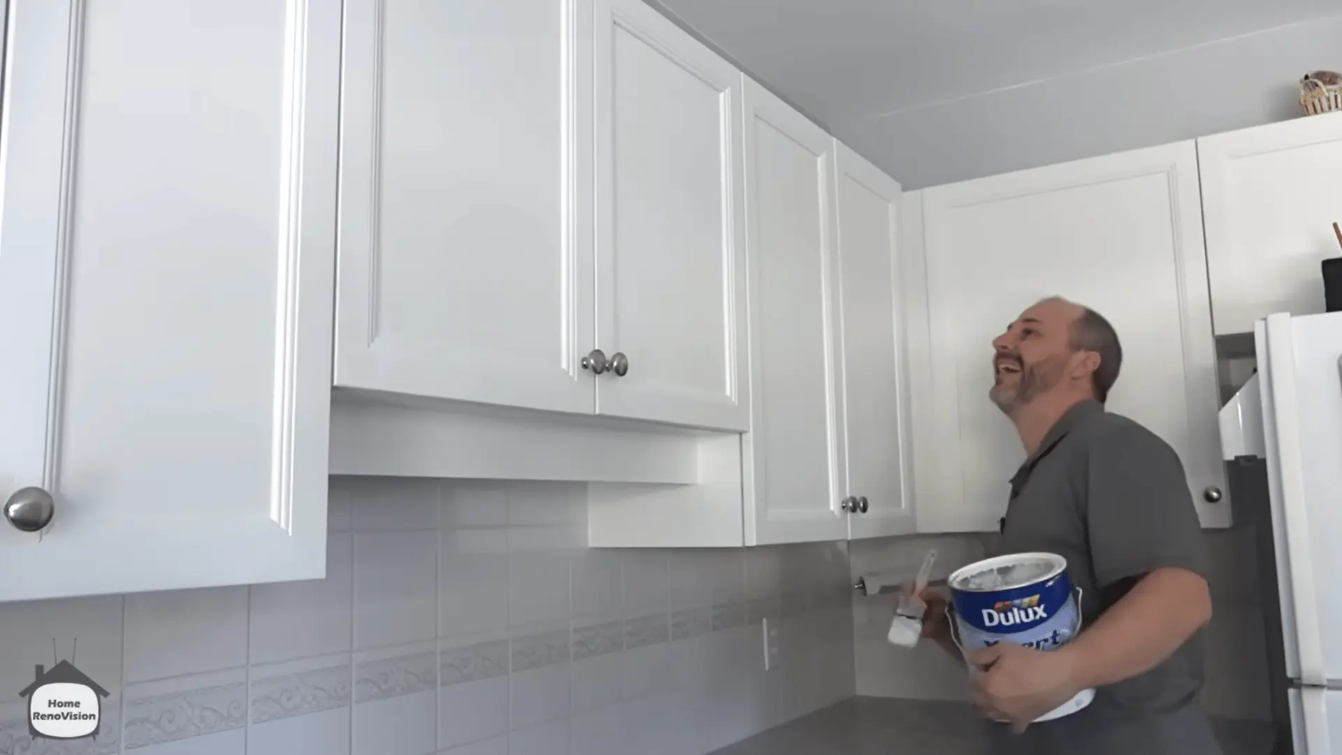 Inspecting the finished white kitchen cabinets for uneven coverage and areas that need paint touch-ups.