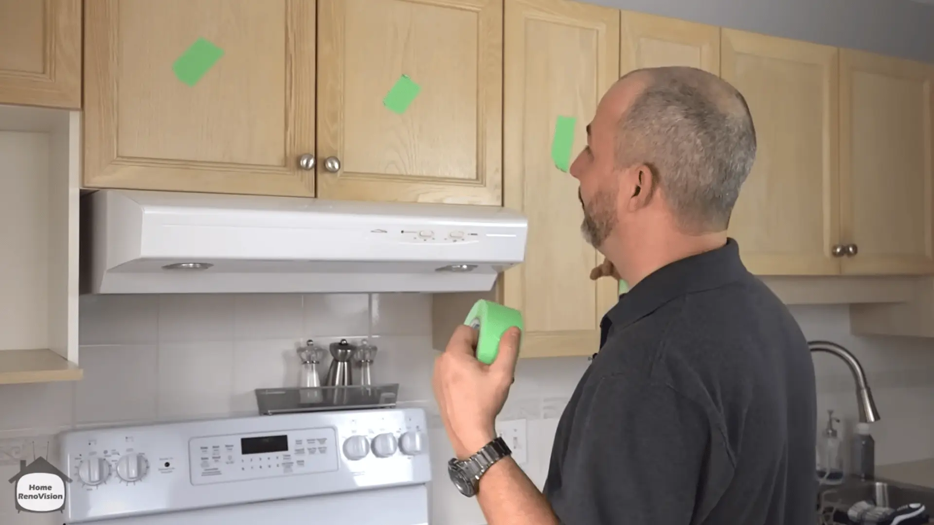 Man labeling kitchen cabinet doors with painter’s tape before removing them for painting.