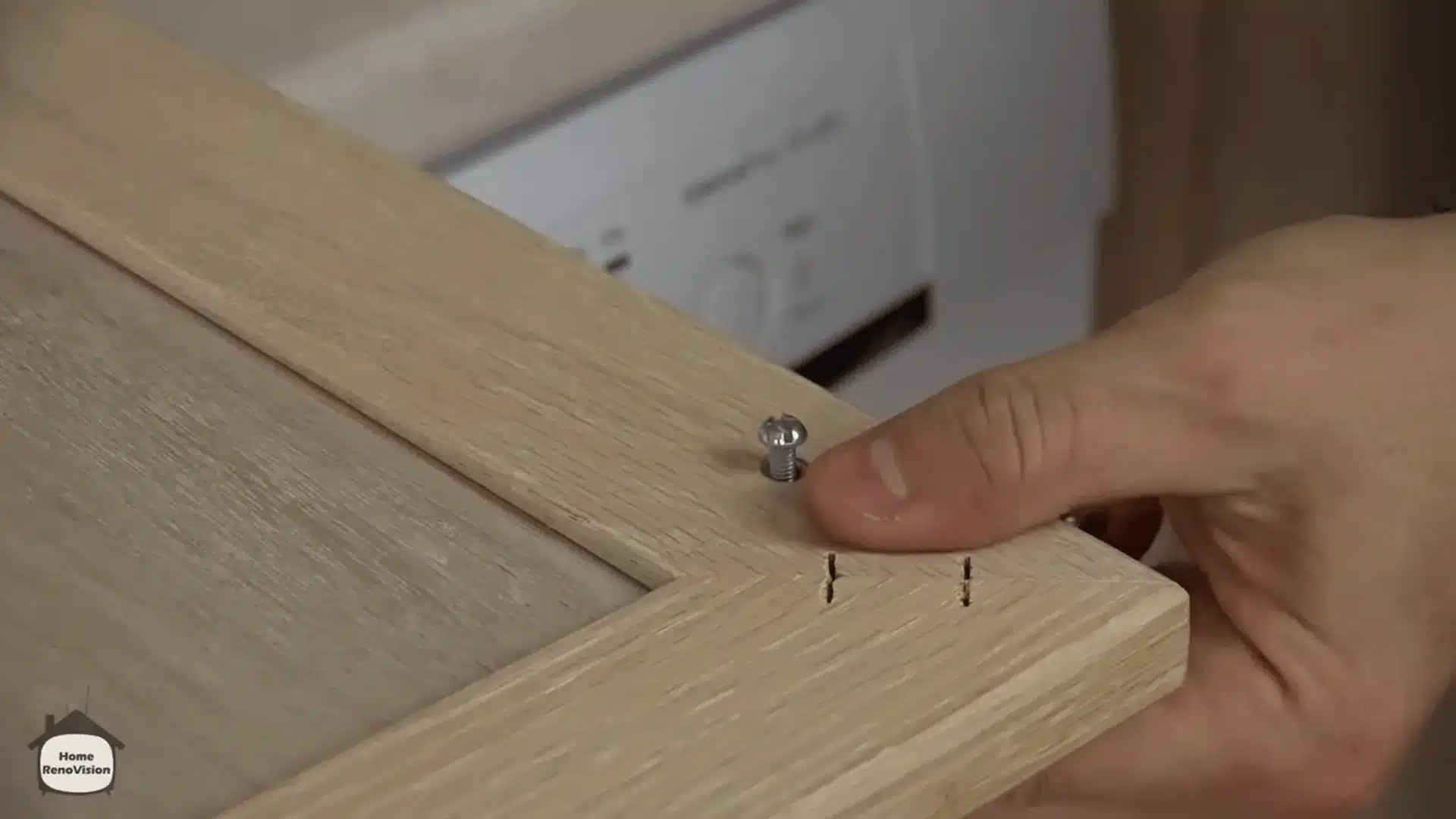 Removing a screw and hardware from a wooden cabinet door before cleaning, sanding, and painting.