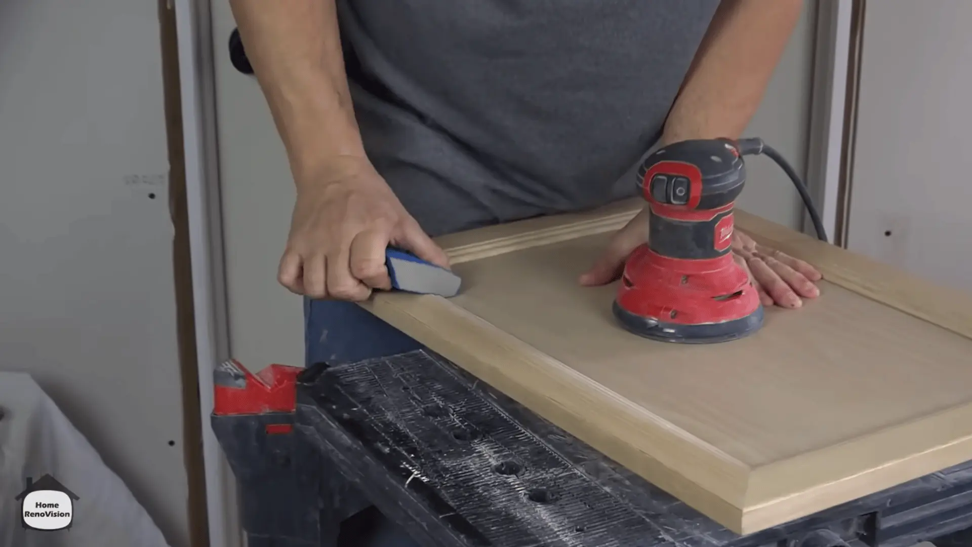 Sanding a wooden kitchen cabinet door with an orbital sander and sanding sponge before priming.