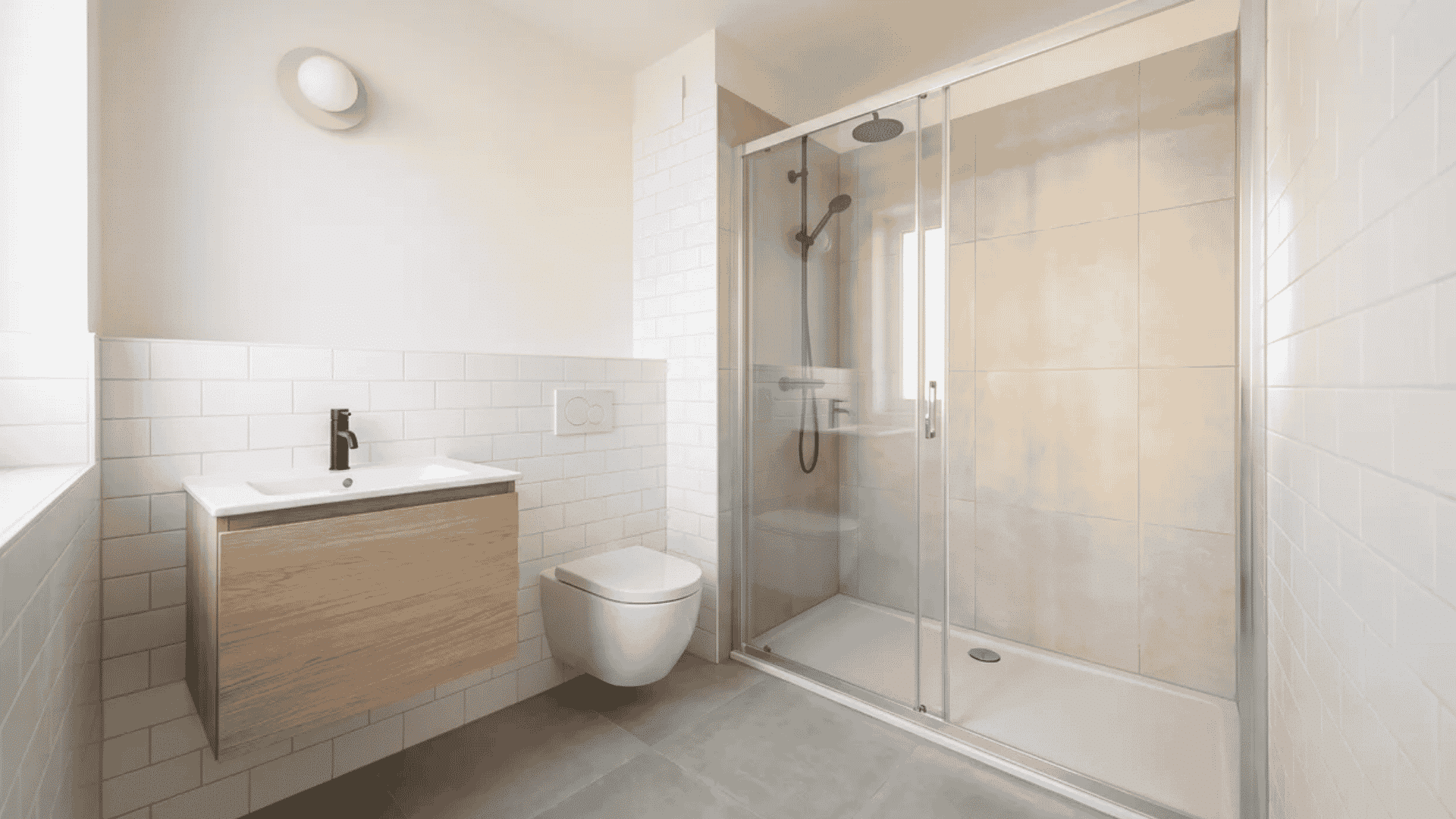 Small modern bathroom with wood vanity, wall-mounted toilet, and glass shower doors