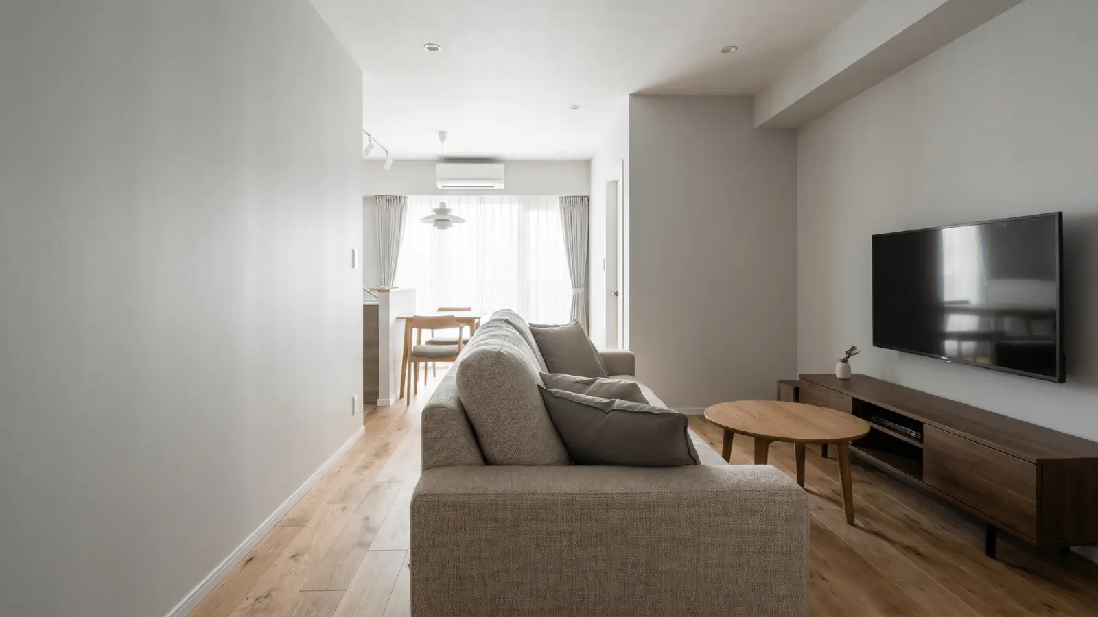 Living room with wall mounted TV, sofa, round coffee table, and wooden media console