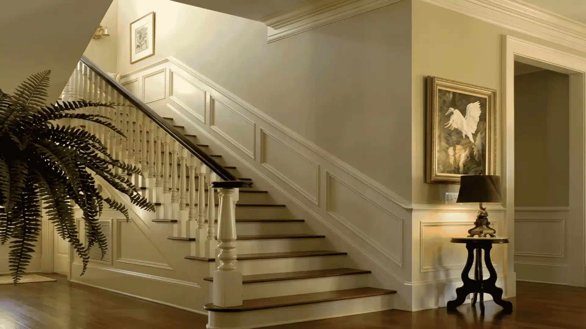 Level crown molding along a hallway ceiling beside a staircase with angled trim on the stair wall.