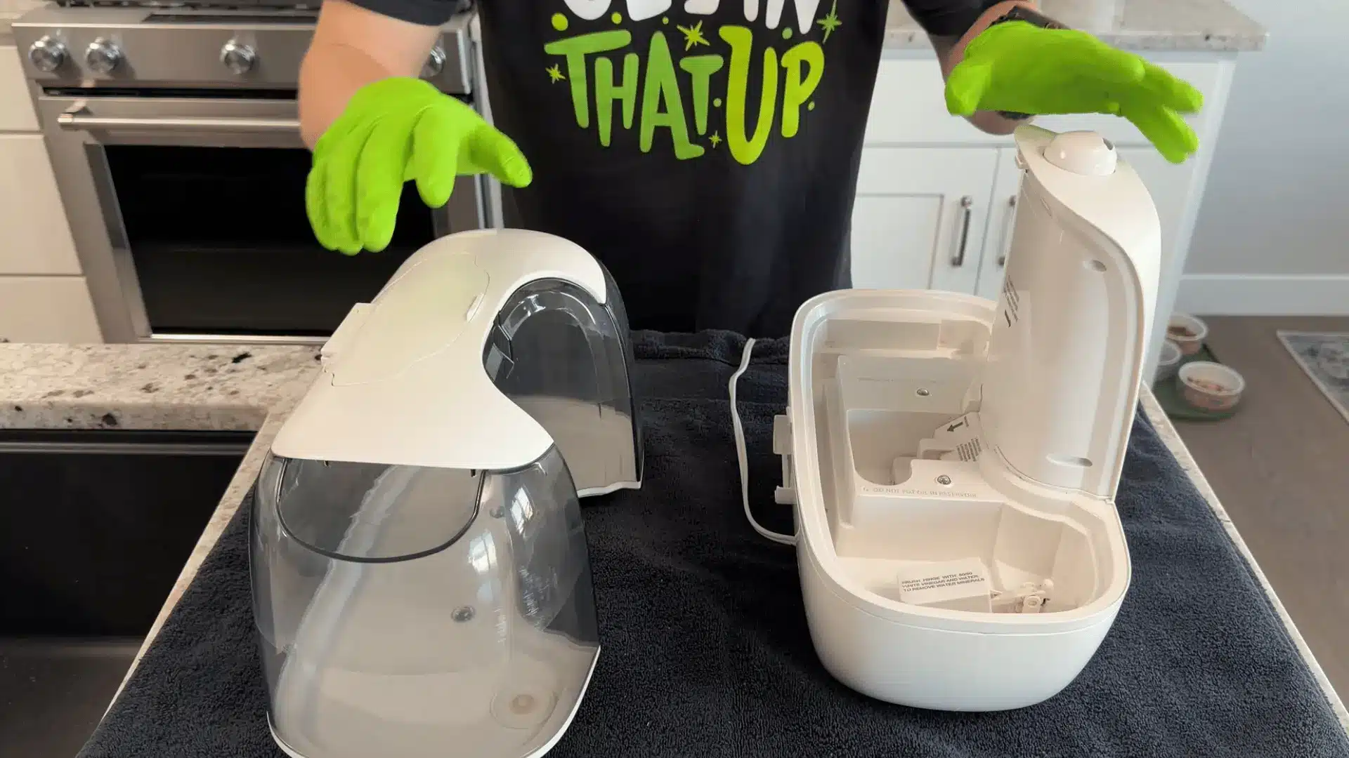 Person cleaning a white humidifier with gloves while the disassembled parts sit on a towel.