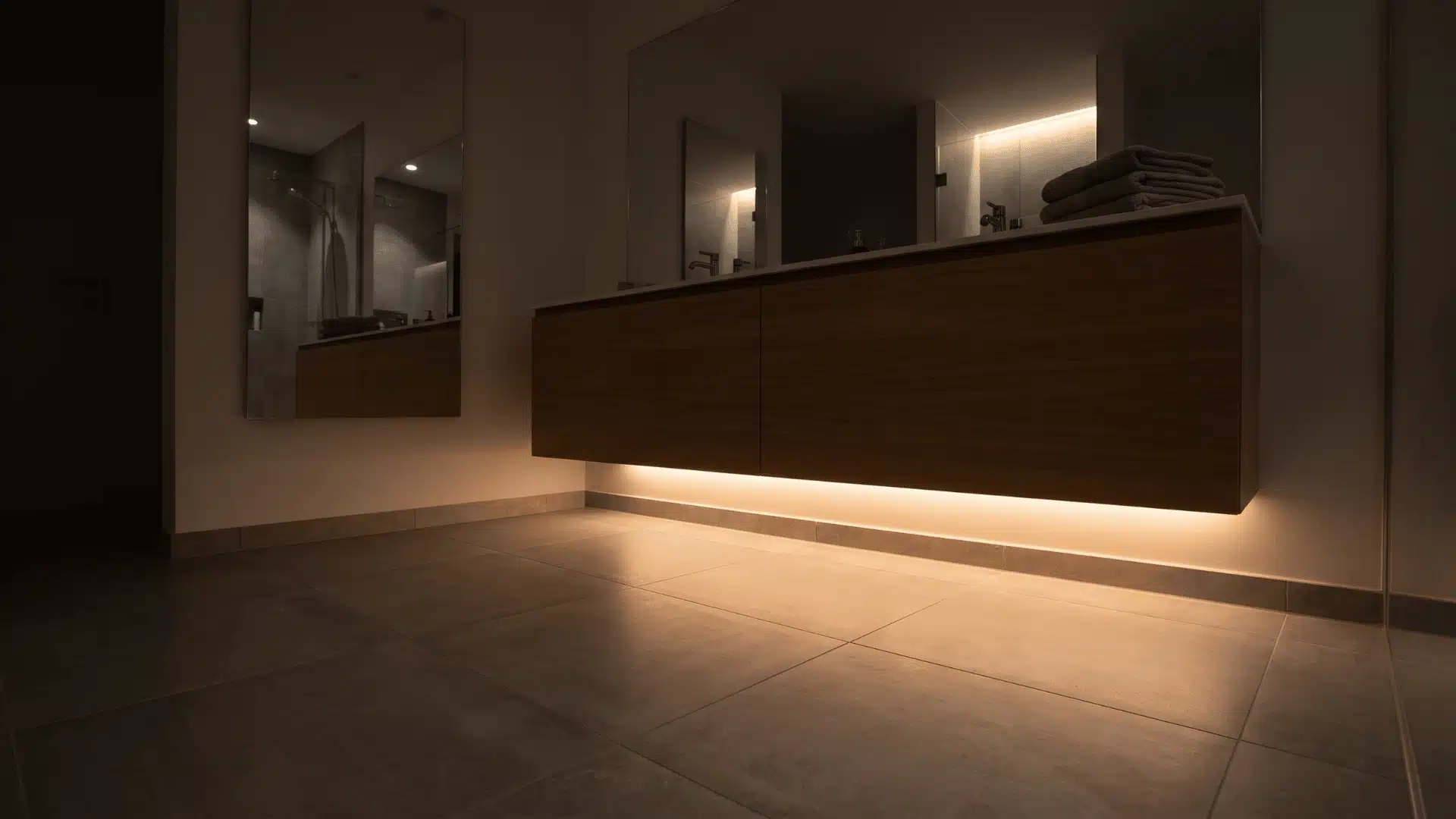 Bathroom vanity with under-cabinet LED strip lighting creating soft floor glow